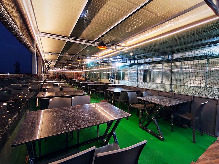 Rooftop café and dining lounge at dusk with granite tables, Vaikuntum Elite Co-Living