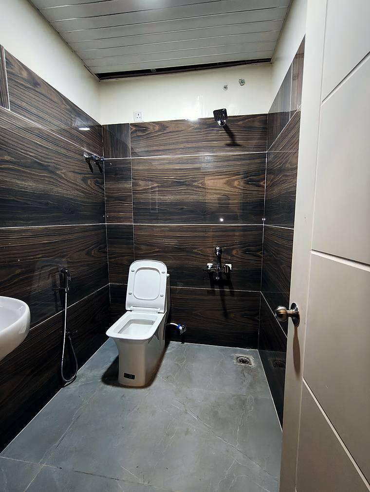 Dark-tiled bathroom with geyser — Vaikuntum Elite Co-Living